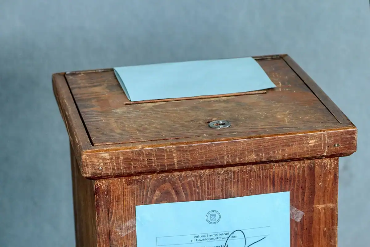 Urnă de vot din lemn cu un buletin albastru introdus în fanta de sus