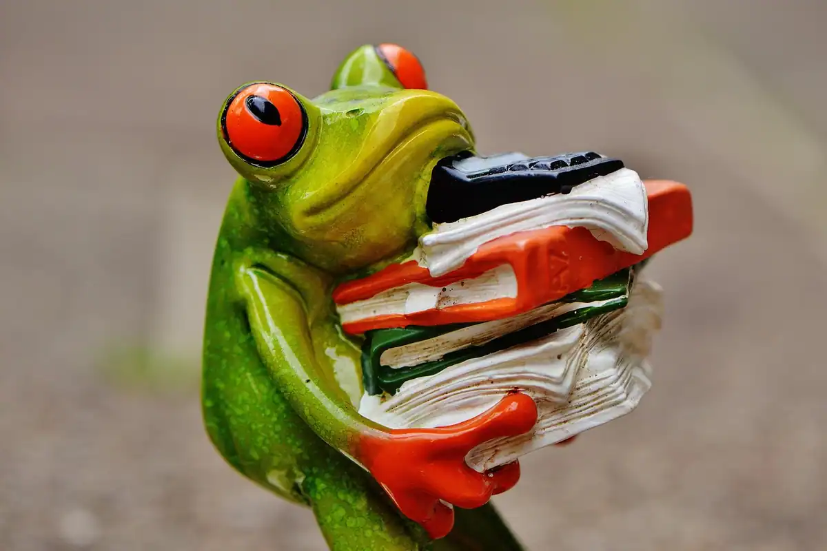 Dosare stivuite pe un birou, lângă un calculator de buzunar și o figurină verde