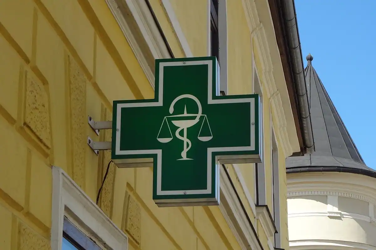 Semn luminos de farmacie cu o cruce verde, montat pe o clădire