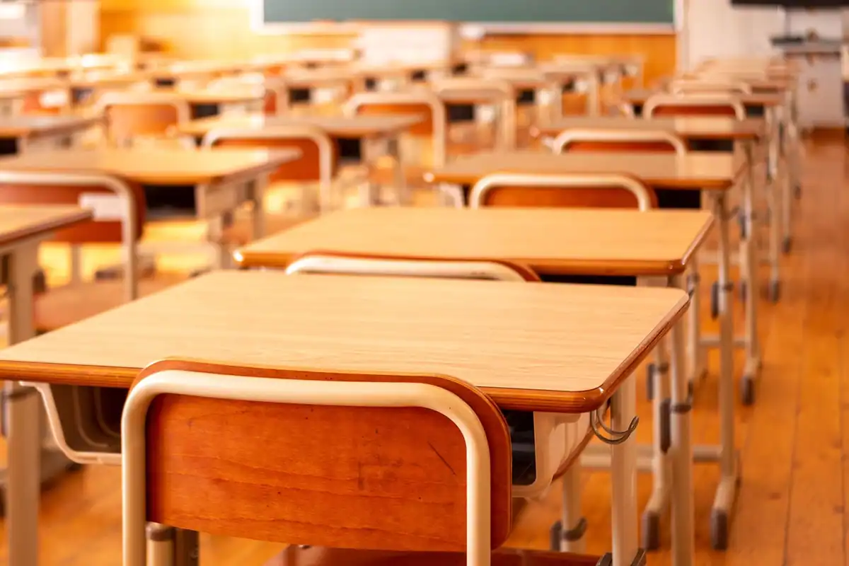 Sală de clasă cu bănci aliniate, goală, pregătită pentru ore