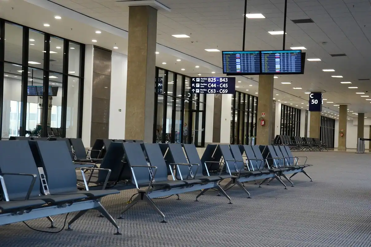 Sală de așteptare dintr-un aeroport, cu pasageri și zone de îmbarcare