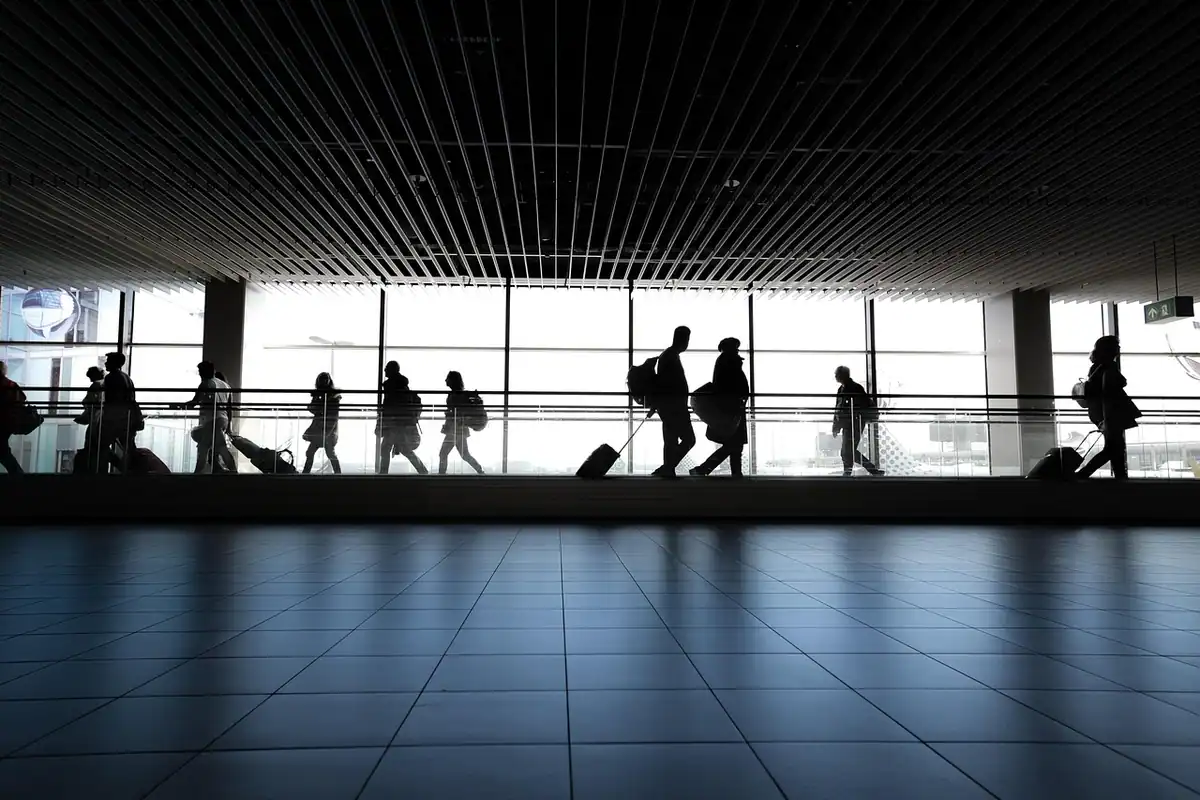 Femeie care merge pe coridorul unui aeroport, în drum spre poarta de îmbarcare