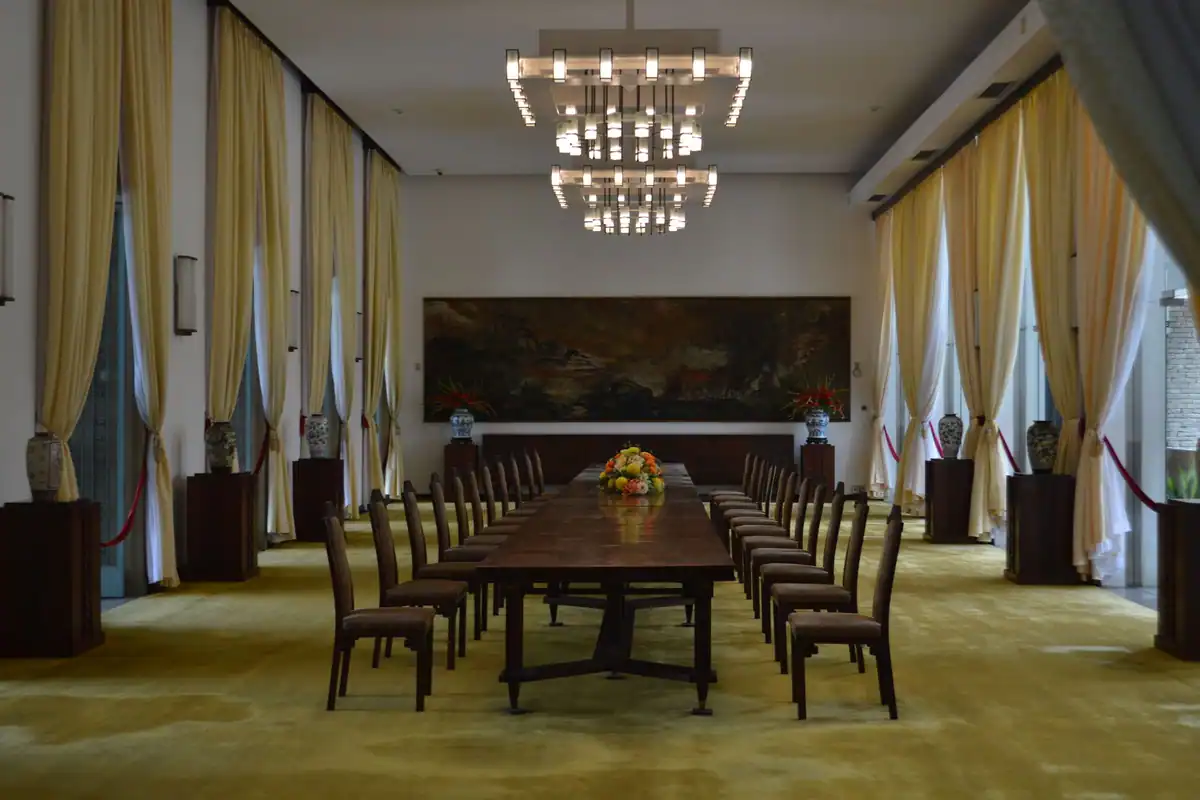 Sală de consiliu cu masă lungă din lemn și candelabre