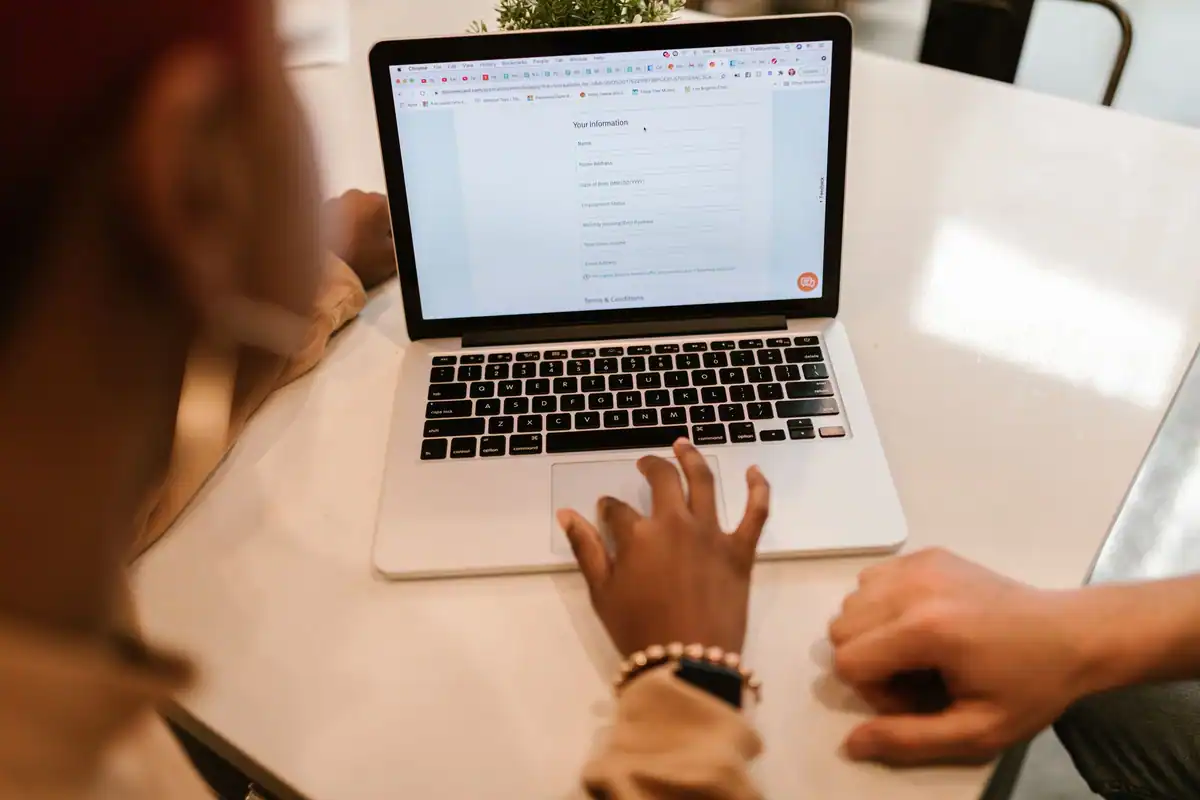 Doi oameni completează un formular online pe un laptop
