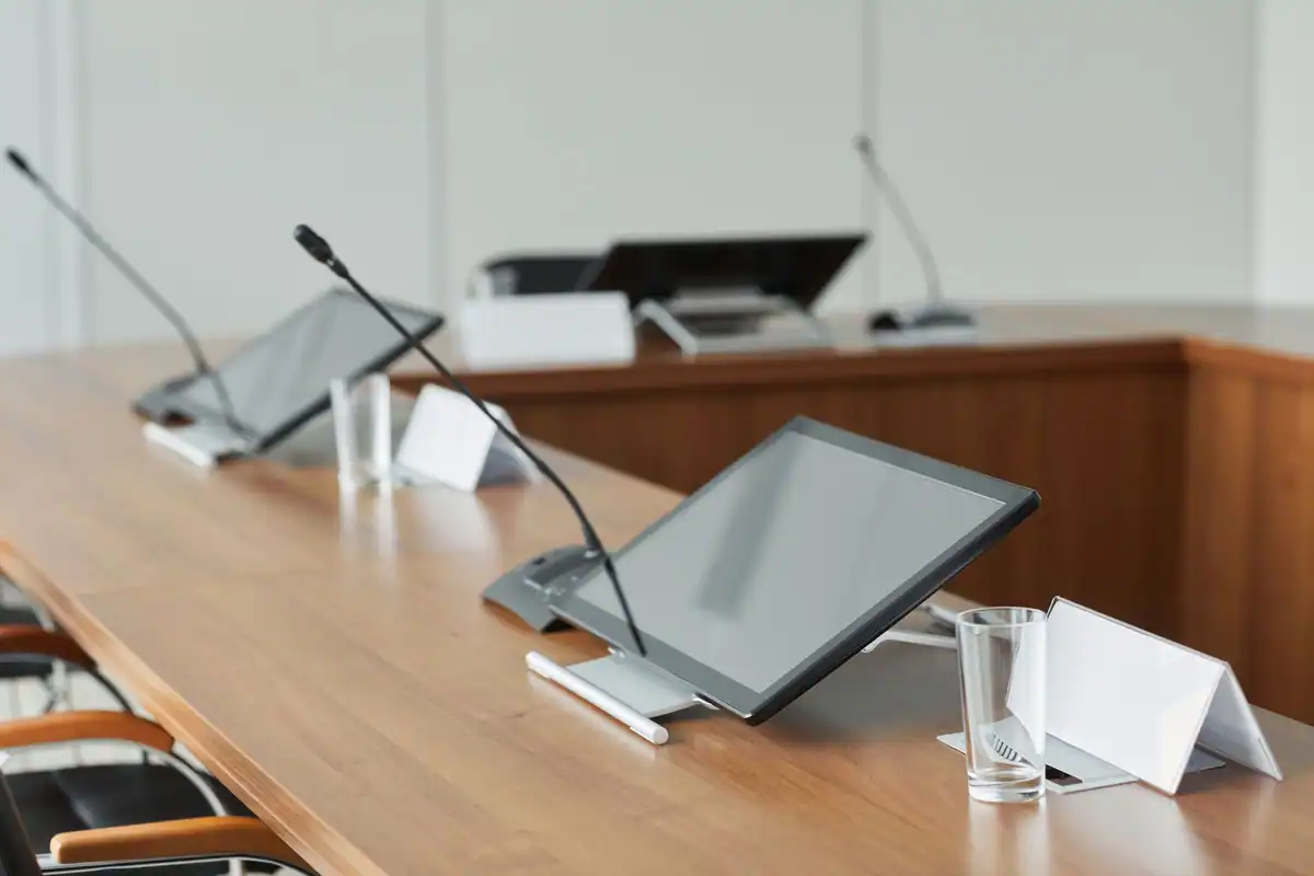Masă de conferință cu microfoane și monitoare într-o sală modernă