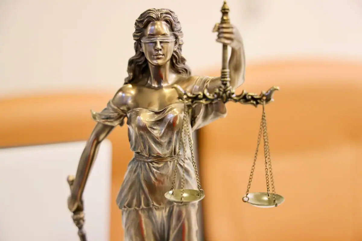 Statuie a Justiției cu balanța în mână, pe fundal cald
