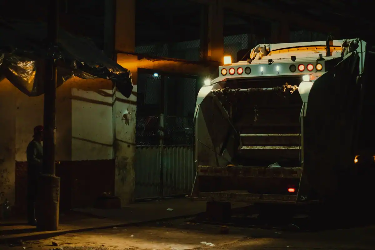 Camion de gunoi pe o stradă luminată noaptea