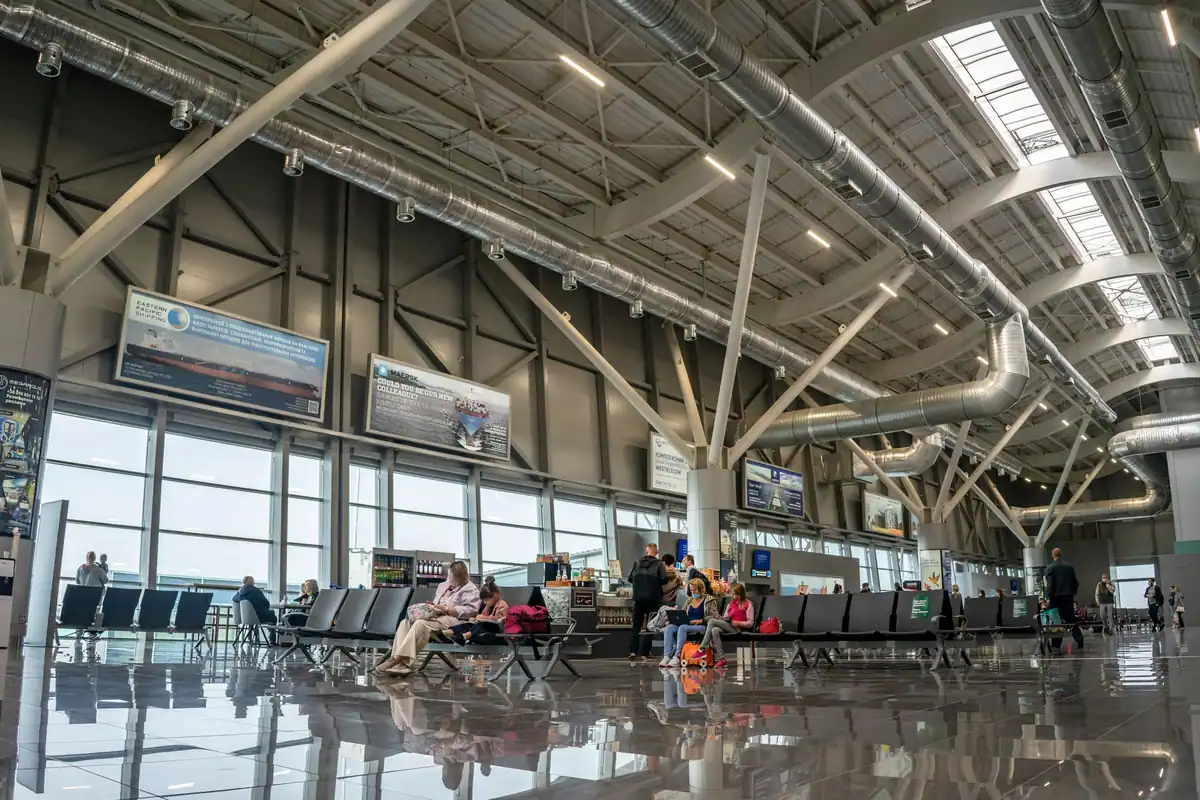 Terminal de aeroport luminos, cu pasageri care așteaptă sau merg